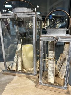 two metal lanterns sitting on top of a wooden table