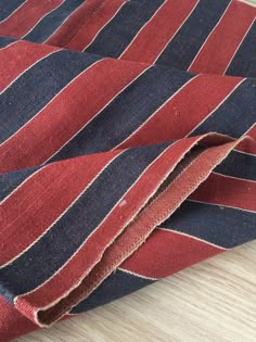 a red, blue and black striped rug on a wooden floor