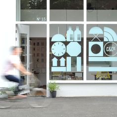 a man riding a bike past a building with windows that have different designs on them