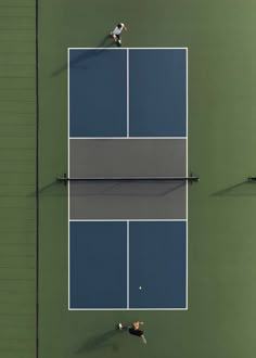 two people playing tennis on a court with blue and green walls, overhead view from above