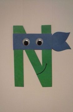 the letter n is made out of paper with eyes and a green leaf on it