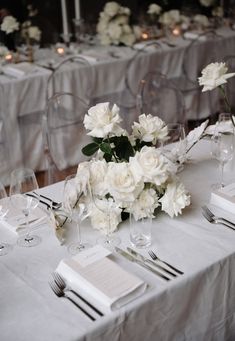 the table is set with white flowers and silverware