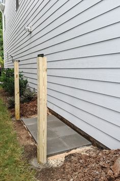 two wooden posts in front of a house with grass and dirt on the ground next to it