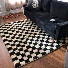 a black and white checkered rug on the floor in a living room with a couch