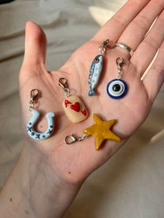 a person's hand holding several charms in the shape of eyeballs and stars