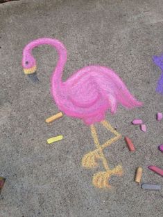 a pink flamingo drawn in chalk on the ground with crayons next to it