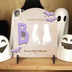 a wooden sign that says, our little b is for halloween with ghost legs and feet