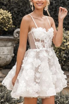 a woman in a short white dress posing for the camera with her hand up to her face