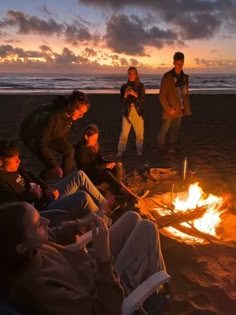 people sitting around a campfire on the beach