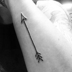 a black and white photo of a woman's arm with an arrow tattoo on it