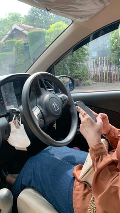 a woman sitting in the driver's seat of a car using her cell phone