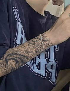 a man with a tattoo on his arm holding a cell phone