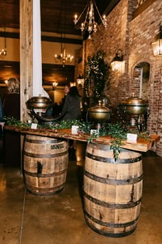 two wooden barrels sitting next to each other on top of a table covered in greenery