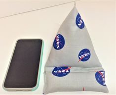 a cell phone sitting on top of a pillow next to a pouch filled with space related items