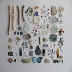 various rocks and plants are arranged on a white surface with wooden sticks, beads, and stones