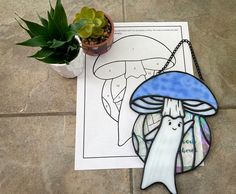 a paper cut out of a mushroom on the ground next to a potted plant