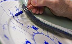 a person using a sharpie to draw on a plate with blue marker and pen