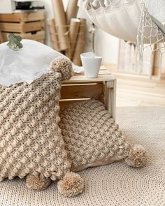 a crocheted teddy bear pillow sitting on top of a table next to a coffee cup