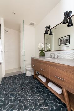 a bathroom with blue and white tile flooring, wooden cabinetry, and mirror