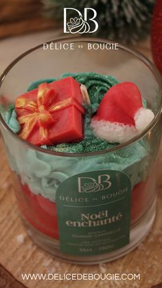 a glass bowl filled with green frosting and red decorations on top of a wooden table