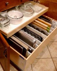 an open drawer in a kitchen filled with dishes and pans