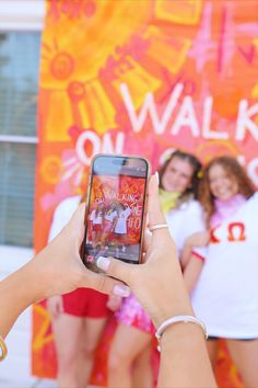 a woman taking a photo with her cell phone while three other women stand behind her