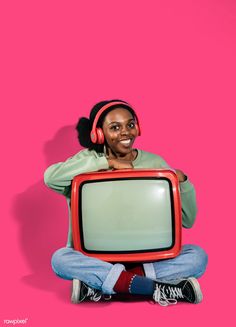 a woman sitting on the floor with an old tv in front of her, wearing headphones