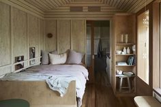 a bedroom with wood paneling and white bedding, along with wooden flooring