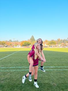 two girls are playing softball on the field in front of an empty field with green grass