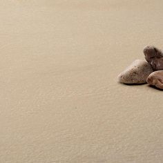 two rocks sitting on top of a sandy beach