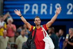 a male tennis player is holding his arms in the air with one hand up and two other hands raised