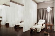 a living room filled with furniture and white drapes hanging from the ceiling over a hard wood floor