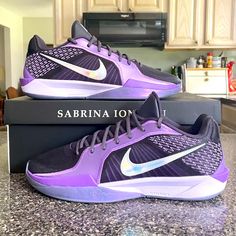 a pair of purple nike basketball shoes sitting on top of a box in a kitchen