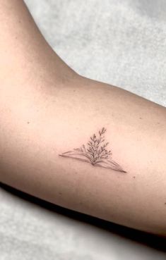 a woman's arm with a small flower tattoo on it