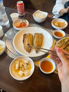 a person holding chopsticks in front of a plate of food on a table