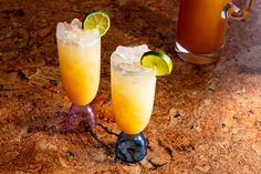 two glasses filled with drinks sitting on top of a counter