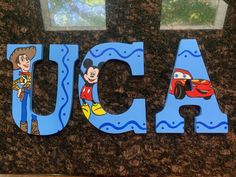 the word aca is made out of wood and painted with mickey mouse, cars