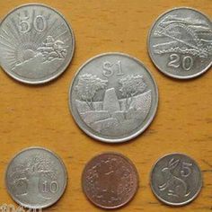 five different coins sitting on top of a wooden table with the numbers 20 and twenty