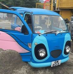 a small blue and pink vehicle parked on top of a dirt field