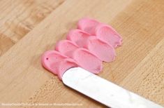 a knife is laying on a cutting board with pink icing