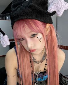 a girl with pink hair wearing a black hat and bunny ears on her head is looking at the camera