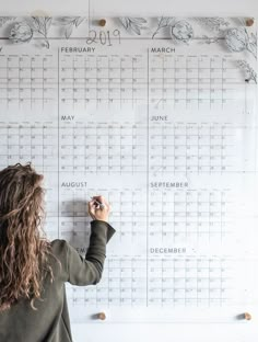 a woman writing on a wall calendar