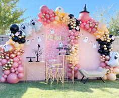 an outdoor party with balloons and decorations on the lawn, including a ghost - themed backdrop