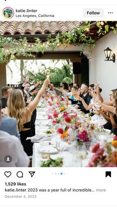 a group of people sitting at a long table with plates and glasses in front of them