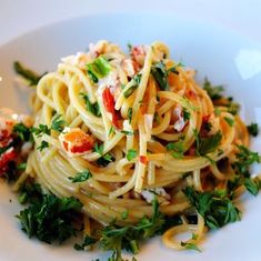 a white plate topped with pasta and garnished with parsley