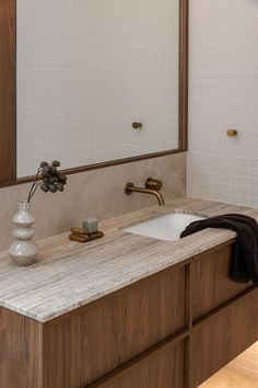 a bathroom sink with a mirror above it and a vase on the counter next to it