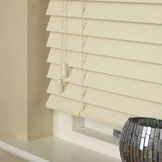 a vase sitting on top of a window sill next to a window blind in a bathroom