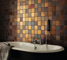 a bath tub sitting next to a wall covered in brown and orange tiles on it's side