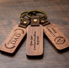 three wooden key chains with engraved labels on them