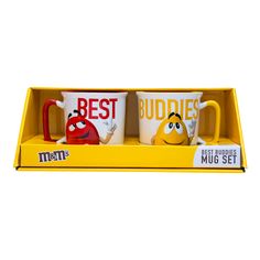 two mugs with the words best buddies on them are in a yellow box,